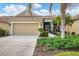 Tan house with two-car garage, landscaping, and a bird statue at 27231 Ipswich Dr, Englewood, FL 34223