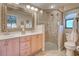 Detailed bathroom featuring a glass door shower, double vanity sink and framed mirror, and a decorated wall at 302 Woodingham Ct, Venice, FL 34292