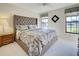 Cozy bedroom featuring a tufted headboard bed, patterned bedding, and natural light from two windows at 302 Woodingham Ct, Venice, FL 34292