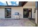 Covered patio area with brick flooring, gas grill, and sliding glass doors to the interior at 302 Woodingham Ct, Venice, FL 34292