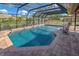 Screened pool with brick border, and view of the surrounding landscape and pond at 302 Woodingham Ct, Venice, FL 34292