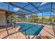 Screened pool area with brick flooring and view of the lush landscaping and blue skies at 302 Woodingham Ct, Venice, FL 34292