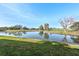 Scenic pond view showcasing serene water, lush green grass, and a line of trees against a clear blue sky at 3500 El Conquistador Pkwy # 333, Bradenton, FL 34210