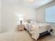 Bedroom with a floral bedspread, window, lamp, and neutral-toned carpet flooring at 3730 82Nd Avenue E Cir # 104, Sarasota, FL 34243