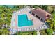 Aerial view of a community pool with lounge chairs, tables, a pavilion, and lush landscaping at 3730 82Nd Avenue E Cir # 104, Sarasota, FL 34243