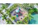 Aerial view of a playground with colorful equipment surrounded by tropical landscaping and a tennis court at 3730 82Nd Avenue E Cir # 104, Sarasota, FL 34243