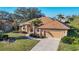 Well-manicured front lawn and mature trees frame this home with a tile roof and two-car garage at 389 Eden Dr, Englewood, FL 34223