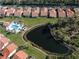 Aerial view of homes with tile roofs surrounding a serene pond at 4951 Summertree Rd, Venice, FL 34293