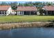 Back exterior view of a home with a pond and well manicured lawn at 4951 Summertree Rd, Venice, FL 34293