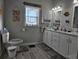 Bathroom featuring a toilet and dual vanity with a window and nautical artwork at 530 Walnut Cir, Venice, FL 34285