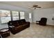 Inviting living room featuring a plush brown leather sofa, tile flooring, and a classic ceiling fan at 5527 20Th W St, Bradenton, FL 34207