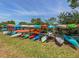 Row of colorful canoes and kayaks stored on a rack by a grassy area, under a partly cloudy blue sky at 590 Portside Dr, North Port, FL 34287