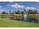 Scenic view of the community entrance with lush landscaping, a pond and a water fountain on a sunny day at 595 Back Nine Dr, Venice, FL 34285