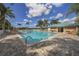 Inviting community pool surrounded by palm trees, lounge chairs and patio seating on a sunny day at 595 Back Nine Dr, Venice, FL 34285