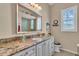 Elegant bathroom featuring granite countertops, a large mirror, and natural light from the window at 612 Cadiz Rd, Venice, FL 34285