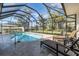 Sparkling swimming pool surrounded by a screened enclosure, lounge chairs, and a beautifully landscaped backyard at 612 Cadiz Rd, Venice, FL 34285