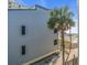 Exterior shot showcasing the building's facade, palm trees, and glimpses of the beach nearby at 700 Golden Beach Blvd # 221, Venice, FL 34285