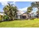 Backyard featuring tropical landscaping, a well-maintained lawn, and a screened-in patio at 734 Brightside Crescent Dr # 18, Venice, FL 34293