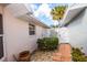 Serene side yard featuring a charming white gate, brick pathway, and lush tropical landscaping at 734 Brightside Crescent Dr # 18, Venice, FL 34293