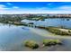 Stunning aerial shot of a waterway with small islands, a rustic bridge, and lush greenery under a vibrant blue sky at 734 Sugarwood Way, Venice, FL 34292