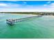 Stunning aerial view of the pier with blue water, sandy beach, and sunny sky perfect for recreation and relaxation at 734 Sugarwood Way, Venice, FL 34292