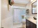 Well-lit bathroom featuring a shower with patterned glass door, white tile, and brown vanity with light countertop at 734 Sugarwood Way, Venice, FL 34292