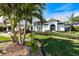 A beautifully landscaped front yard with palm trees and neatly trimmed shrubs leading up to a white single Gathering home at 734 Sugarwood Way, Venice, FL 34292