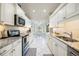 Modern kitchen featuring white cabinets, granite countertops, and stainless steel appliances at 734 Sugarwood Way, Venice, FL 34292