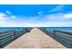 Pier view featuring wooden plank walkway to the sea, benches for relaxation, with calming ocean view under blue sky at 734 Sugarwood Way, Venice, FL 34292