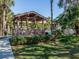 Charming gazebo in a community area with lush landscaping and blue umbrellas at 748 White Pine Tree Rd # 208, Venice, FL 34285