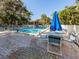 Community pool deck with lounge chairs and tables and shady umbrellas at 748 White Pine Tree Rd # 208, Venice, FL 34285