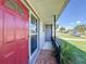 Cozy front porch featuring mosaic tiling, decorative handrail and a red front door at 7903 Hyde Park Ave, North Port, FL 34287