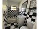 Black and white bathroom with checkerboard tile, a white vanity, and a shower-tub combo at 807 Lucille Ave, Nokomis, FL 34275