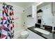 Bright bathroom with a shower-tub combo, black countertop vanity, and geometric shower curtain at 8475 Chesapeake Ave, North Port, FL 34291