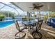 Covered outdoor lanai featuring comfortable seating, ceiling fan, and views of the backyard pool area at 8475 Chesapeake Ave, North Port, FL 34291