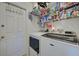 Well-organized laundry room with washer, dryer, shelving, and storage, next to a white door at 8475 Chesapeake Ave, North Port, FL 34291