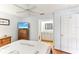 Another angle of the bedroom shows an adjacent bathroom, ceiling fan, and wood-look floors at 9790 Parkwood Ct, Seminole, FL 33777