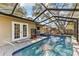 The pool features an attached spa and is enclosed within a screen; the home can be accessed through the french doors at 9790 Parkwood Ct, Seminole, FL 33777