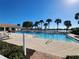 Community pool with lounge chairs and beautiful palm trees in the background, under blue sky at 13892 Alafaya St, Venice, FL 34293