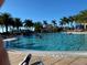 Large community pool with people swimming and palm trees in the background under blue sky at 13892 Alafaya St, Venice, FL 34293