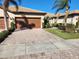 Charming home featuring a two-car garage, tile roof, paver driveway, and tropical landscaping at 13892 Alafaya St, Venice, FL 34293