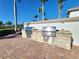 Outdoor grilling area with brick pavers, stone counter, palm trees and landscaping in a lovely outdoor setting at 13892 Alafaya St, Venice, FL 34293