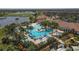 Scenic aerial view of the community featuring a large pool, clubhouse, and lush landscaping by a serene lake at 10181 Colubrina Dr, Venice, FL 34293