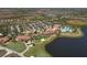 Aerial of community clubhouse, pool, tennis courts, parking, and lush landscaping on a scenic lake at 10181 Colubrina Dr, Venice, FL 34293