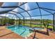 Screened-in pool and spa with brick patio, sunny skies, and scenic lake views at 10181 Colubrina Dr, Venice, FL 34293
