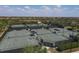 Aerial view of community tennis courts, featuring multiple well-maintained courts and shaded seating areas at 10181 Colubrina Dr, Venice, FL 34293