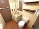 Small half-bathroom featuring a built-in sink and cabinet, toilet, dark brown shelves, and light walls at 105 Lakeview Dr, North Port, FL 34287