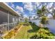 Well-maintained backyard with a lush green lawn, vibrant plants, a white fence, and a screened-in lanai at 1181 Southland Rd, Venice, FL 34293
