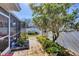 Charming backyard featuring a brick walkway, lush greenery, a privacy fence, and a screened patio at 1181 Southland Rd, Venice, FL 34293