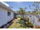 A well-manicured backyard features a screened patio, mature landscaping, grass, and a white privacy fence at 1181 Southland Rd, Venice, FL 34293